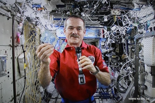Canadian Space Agency astronaut Chris Hadfield, the commander of the International Space Station (ISS), holds the newly unveiled 5-dollar polymer bank note via video conference call from the space station orbiting more than 350 kilometres above earth for the unveiling event taking place at the Bank of Canada in Ottawa, Canada, April 30, 2013. Canada' s central bank on Tuesday added the last two banknotes to its polymer note series, which started in 2011 in its latest efforts to fight against counterfeit currency. (Xinhua/James Park) 