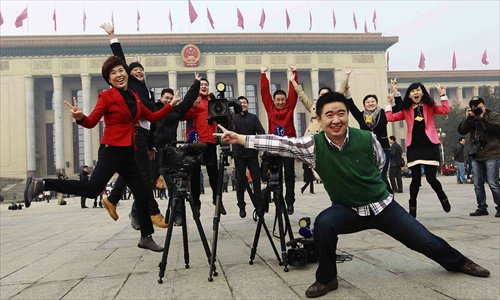 Reporters pose for photos in front of the Great Hall of the People in Beijing after the closing meeting of the first session of the 12th National People's Congress Sunday. Photo: CFP