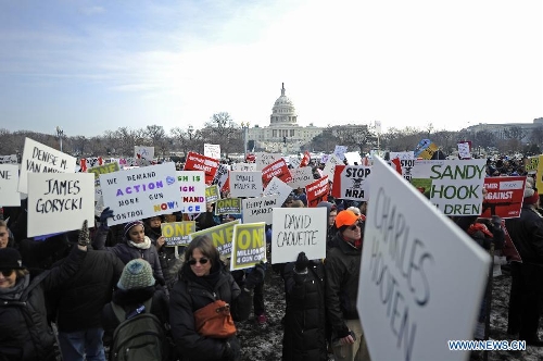 People hold signs with names of gun violence victims in front of the Capitol Hill during a march in Washington D.C., capital of the United States, Jan. 26, 2013. Thousands of people, including family members of victims and survivors of shootings at Virginia Tech University, Sandy Hook elementary school and others, took part in a march for stricter gun control laws here on Saturday. (Xinhua/Zhang Jun) 