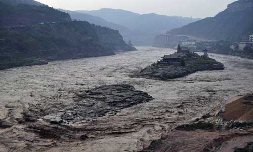 The Mengmenshan scenic area is surrounded by flood water in the lower reaches of the Hukou Waterfall in northwest China's Shaanxi Province, July 28, 2012. The Hukou scenic area has been closed to visitors in anticipation of the largest flood peak to hit the Yellow River, China's second longest, since 1989. Photo: Xinhua