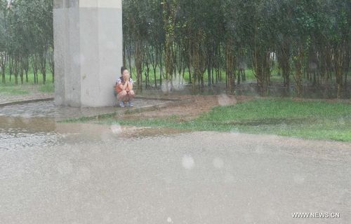 A woman takes shelter from the rain beside a pier in Tianjin, North China, July 26, 2012. Heavy rainfall hit the municipality from Wednesday afternoon to Thursday. Photo: Xinhua

