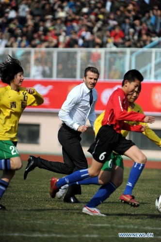 British soccer player David Beckham (C) plays soccer with students at the Qingdao Tiantai Stadium in Qingdao, east China's Shandong Province, March 22, 2013. Beckham visited Qingdao Jonoon Soccer Club as the ambassador for the youth football program in China and the Chinese Super League Friday. (Xinhua/Li Ziheng)