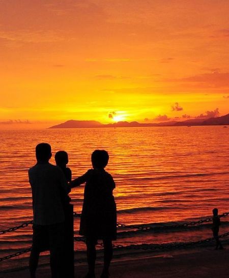 A family stand by the sea in the afterglow at Sanya Bay in Sanya, South China's Hainan Province, August 20, 2012. Photo: Xinhua