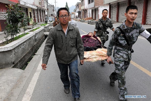 Soldiers and volunteers carry an injured person to the hospital in the Longmen Township, Lushan County, southwest China's Sichuan Province, April 21, 2013. Military and civilian rescue teams are struggling to reach every household in Lushan and neighboring counties of southwest China's Sichuan Province, badly hit by Saturday's strong earthquake. (Xinhua/He Junchang) 