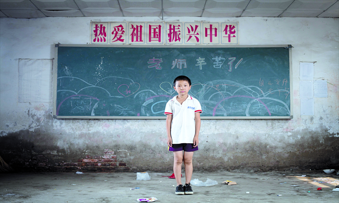  Xu Shangchen, 11, from Heilongjiang Province, stands in an empty classroom in a deserted school for the children of migrant workers in Magezhuang village, Chaoyang district, Beijing, on August 26. The school was closed for sub-standard education facilities in June. All the students were sent to other neighboring schools. Photo: CFP