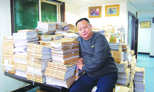 Zhou Litai leans against the piles of case files in his office in Chongqing.Photo: Courtesy Zhou Litai