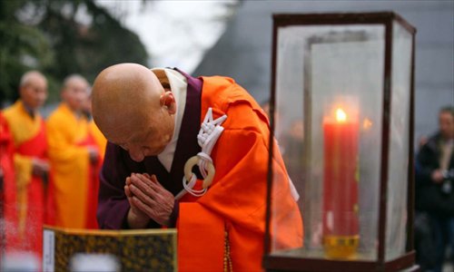 A Japanese monk prays in front of a memorial wall on which names of the Nanjing Massacre victims are engraved, during a religious service at the Memorial Hall of the Victims in Nanjing Massacre by Japanese Invaders in Nanjing, capital of east China's Jiangsu Province, December 13, 2012, to mark the 75th anniversary of the Nanjing Massacre. Nanjing was occupied on December 13, 1937, by Japanese troops who began a six-week massacre. Records show more than 300,000 Chinese unarmed soldiers and civilians were killed. Photo: Xinhua
