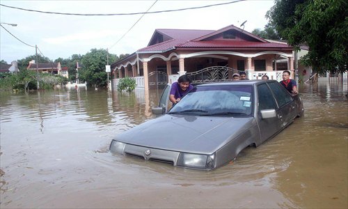 Family members push their car through the flood waters in Malaysia's Terengganu state on Thursday. Floods triggered by torrential monsoon rains in Malaysia have claimed the life of a second victim even though waters have subsided, allowing some evacuees to return home from relief centers, reports said. Photo: AFP