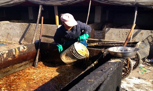 A farmer takes swill to feed pigs at her farm in Langfang, Hebei Province, on April 11. Photo: CFP