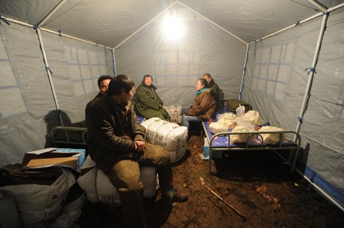 Villagers sit in a tent at Yudong Village of Longchang Township in Kaili, southwest China's Guizhou Province, Feb. 18, 2013. Five people, including two children, were buried after a landslide hit the village around 11 a.m. Monday. Relief work was hampered as sporadic slides continued. (Xinhua/Tao Liang)&nbsp; 
