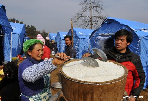 People from nearby villages cook for landslide-affected people at Gaopo Village in Zhenxiong County, southwest China's Yunnan Province, Jan. 12, 2013. Landslide-affected villagers in Gaopo Village have been temporarily settled in tents and got life necessities. Forty-six people were killed in the Friday landslide. Another two people were injured. (Xinhua/Chen Haining) 