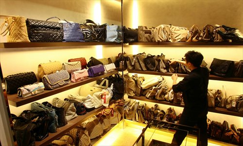 A store attendant arranges handbags at a secondhand luxury goods store. Photo: IC