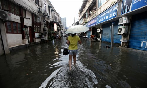 A woman walks through a flooded street in Shanghai's Hongkou district on Friday afternoon, when the city for the first time in four years saw a red rainstorm alert, the highest in the official four-level warning system. The Shanghai Meteorological Bureau issued an orange rainstorm alert at 1:35 pm, which was upgraded to red 26 minutes later, indicating precipitation of more than 100 millimeters. The thunderstorms also paralyzed some of Shanghai's metro lines and arterial roads, while the city's two airports - Hongqiao and Pudong - were barely affected. The highest hourly precipitation was spotted in Pudong with 124 millimeters. Photo: IC