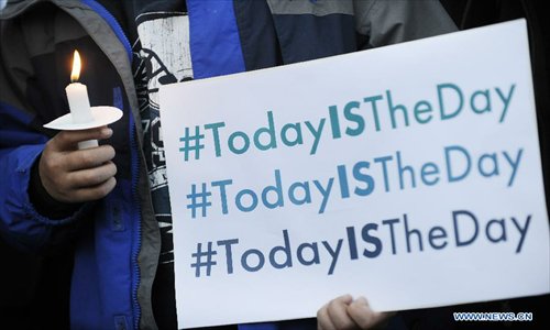 A supporter of gun control legislation holds a candle and a placard during a rally to pay respect for the shooting victims in front of the White House in Washington, capital of the United States, Dec. 14, 2012, following a deadly shooting spree in an elementary school in Newtown, Connecticut, which took place earlier in the day. Photo: Xinhua