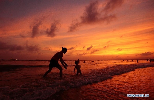 People enjoy themselves on a beach at sunset in Sanya, south China's Hainan Province, May 16, 2013. (Xinhua/Chen Wenwu)&nbsp; 