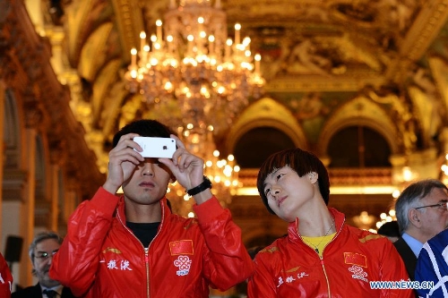 Chinese player Zhang Jike (L) takes photos as his compatriot Ding Ning looks on during the official draw of the upcoming World Table Tennis Championships in Paris, France, May 11, 2013. The world championships will kick off on May 13 and the final event will be held on May 20. (Xinhua/Tao Xiyi) 