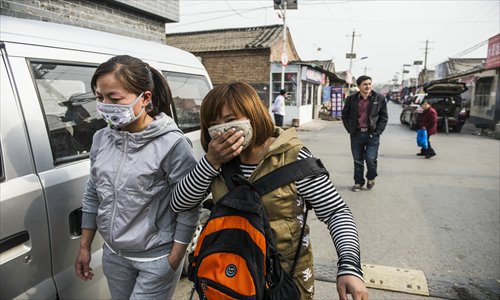 Two local residents wearing masks pass by the home of a four-year-old H7N9 flu virus carrier surnamed Zhu in Naidong village, Chaoyang district, Beijing, on Monday. Photo: Li Hao/GT
