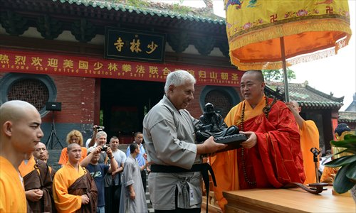 Shaolin Temple Abbot Shi Yongxin gives an American student a Buddhist statue at the ceremony. Photo: IC

