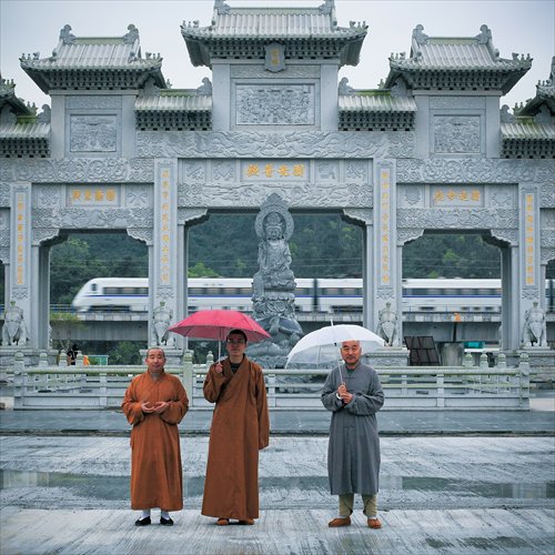 Monks stand in front of an arch, behind which the railway passes. Photo: IC