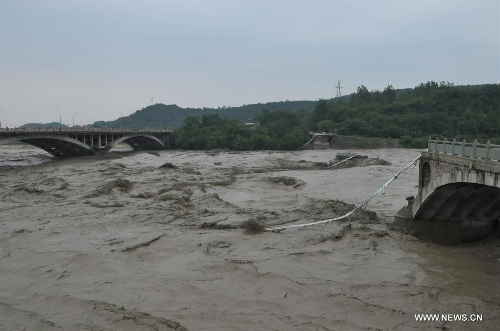 Photo taken on July 9, 2013 shows the collapsed old Qinglian Bridge (R) across the Tongkou River in Jiangyou City, southwest China's Sichuan Province. The neighboring bridge on the left is the Qinglian Bridge. An unknown number of vehicles and pedestrians fell into the river after the bridge collapsed on the morning of July 9. The water level of the river rose significantly over the past two days due to continuous rainfalls in the region. (Xinhua)