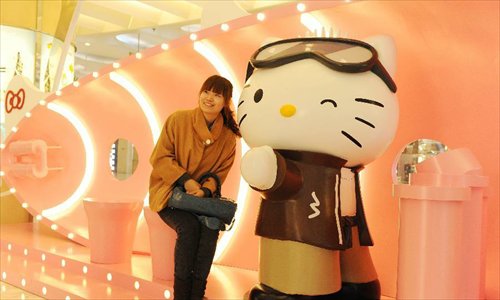 A young woman poses for pictures with a Hello Kitty in the Joy City in east China's Shanghai Municipality, Nov. 26, 2012. A big Hello Kitty exhibition themed on Hello Kitty's exploration in the polar regions would last from Nov. 24, 2012 to Feb. 24, 2013 in Shanghai. Photo: Xinhua
