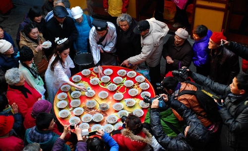  Citizens get porridge distributed by a performer acting as Madame White Snake, a white snake taking on a woman's form in a Chinese folk tale, at the Xuanzang Temple in Nanjing, capital of east China's Jiangsu Province, Jan. 19, 2013, to celebrate the traditional Laba Festival. Laba literally means the eighth day of the 12th lunar month. The Laba Festival is regarded as a prelude to the Spring Festival, or Chinese Lunar New Year, the most important occasion of family reunion, which falls on Feb. 10 this year. Eating porridge is an old tradition on the Laba Festival in China. Many temples also have the tradition of offering porridge to the public to commemorate Buddha and deliver his blessings to both believers and non-believers. (Xinhua/Li Xiang) 