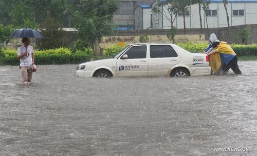 People push a car in Tianjin, North China, July 26, 2012. Heavy rainfall hit the municipality from Wednesday afternoon to Thursday. Photo: Xinhua


