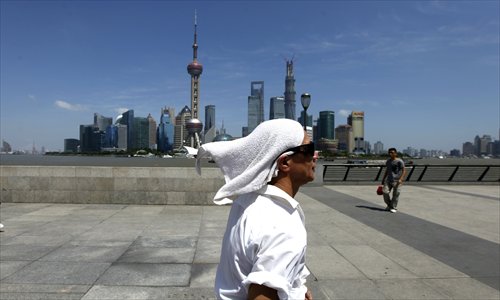 A visitor wearing a wet towel walks by the Bund Sunday. The high temperature in Shanghai fell to 34 C over the weekend due to the effects of typhoon Soulik. The hot weather is expected to return later this week, with the temperature peaking around 38 C. Photo: Cai Xianmin/GT