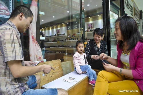 Shop owners play poker in their leisure time at a commercial pedestrian street in the city of Hotan, northwest China's Xinjiang Uygur Autonomous Region, July 1, 2013. (Xinhua/Zhao Ge)