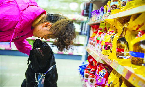 Jennifer, a Labrador guide dog, helps her blind master Chen Yan choose dog food at a Changping district mall. Photo: Li Hao/GT