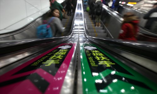 Commuters ride the escalators in the transfer hall at People's Square Station Tuesday afternoon. The local metro operator has replaced the signs advising riders to 