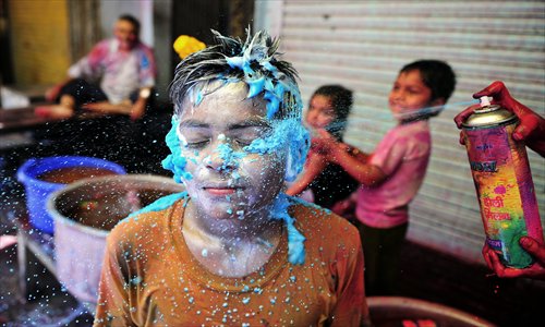 A young Indian reveller is sprayed in the face with colored foam during Holi festival celebrations in Allahabad on Wednesday. Holi, the Festival of Colors, is a popular Hindu spring festival observed in India and Nepal at the end of winter season on the last full moon day of the lunar month. Photo: AFP