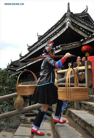 A woman of the Dong ethnic group carries food walking by the Chengyang Fengyu Bridge in Sanjiang Dong Autonomous county, South China's Guangxi Zhuang Autonomous Region, December 1, 2012. A celebration ceremony was held on Saturday to mark the 100th anniversary of the completion of Chengyang Fengshui Bridge. Built in 1912, the 77.76-meter-long bridge is famed for its combination of bridge, veranda and Chinese pavilion. (Xinhua/Lai Liusheng) 



