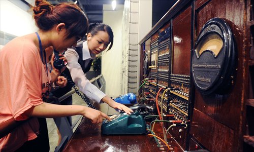 A visitor to the Shanghai Telecom Museum tries to figure out an old switchboard and telephone. Photo: CFP