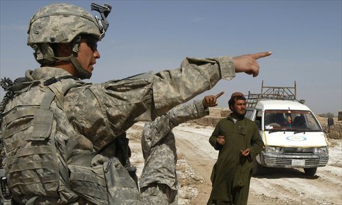A US soldier and his interpreter, ask an Afghan motorist to drive away from their outpost in the Badula Qulp area, west of Lashkar Gah in Helmand province, southern Afghanistan on February 20, 2010. Photo: IC