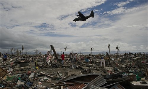 Super Typhoon Haiyan victims sift through the rubble of their destroyed homes as a military cargo plane flies overhead in Tacoblan on Wednesday. The United Nations has confirmed at least 4,500 deaths in the disaster. Photo: AFP