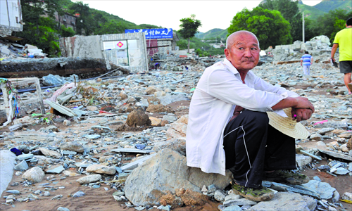 An old man sits on the debris in Tanmugang village, Fangshan district. Photos: CFP