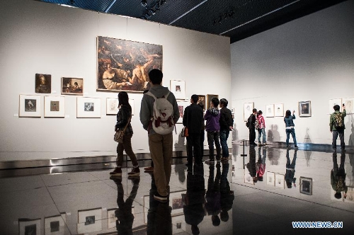 Visitors look at paintings during the 