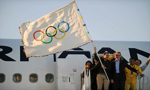 Rio de Janeiro's Mayor Eduardo Paes (left) waves the Olympic flag upon arriving home on Monday. Photo: AFP