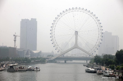 Fog-shrouded buildings are pictured in Tianjin, north China, June 18, 2013. Local meteorological authorities issued a yellow fog alert on Tuesday morning. (Xinhua/Liu Dongyue)