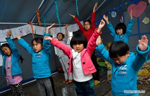 Children take a dance class in a temporarily-erected tent in Lushan County, southwest China's Sichuan Province, May 17, 2013. More than 100 children frequently participate in extra-curricular activities at this temporary school, which was opened on April 29 by volunteers and provides reading, painting and dancing classes to local children. The county was jolted by a 7.0-magnitude earthquake on April 20. (Xinhua/Liu Xiao) 