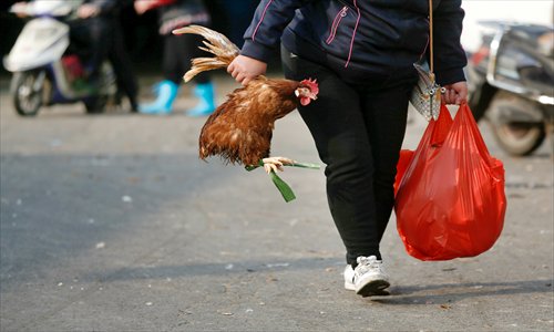 A resident carries a chicken from a market in Shanghai on January 5, 2014. Photo: IC