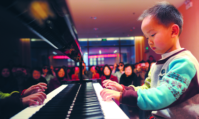 A kid plays the piano in front of an audience of adults in Wuhan, Hubei Province. Photo: CFP