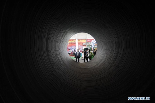 Visitors view a drainage pipe during the 2013 China (Shenyang) International Architecture Exposition in Shenyang, capital of northeast China's Liaoning Province, May 20, 2013. The three-day expo kicked off on Monday, with 615 enterprises from home and abroad participated. (Xinhua/Yang Qing)