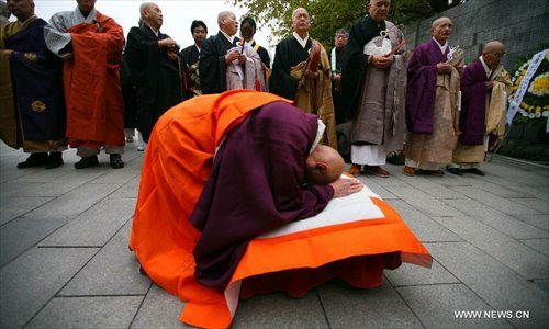 Japanese monks pray in front of a memorial wall on which names of the Nanjing Massacre victims are engraved, during a religious service at the Memorial Hall of the Victims in Nanjing Massacre by Japanese Invaders in Nanjing, capital of east China's Jiangsu Province, December 13, 2012, to mark the 75th anniversary of the Nanjing Massacre. Nanjing was occupied on December 13, 1937, by Japanese troops who began a six-week massacre. Records show more than 300,000 Chinese unarmed soldiers and civilians were killed. Photo: Xinhua