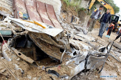Local residents stand by a car stuck in mud in Beni Messous suburb, in upper Algiers, Algeria, on May 22, 2013. Heavy rain poured since Tuesday in several provinces in northern part of the country, claiming the life of one citizen, injuring three others, and causing extensive damages. (Xinhua/Mohamed Kadri) 