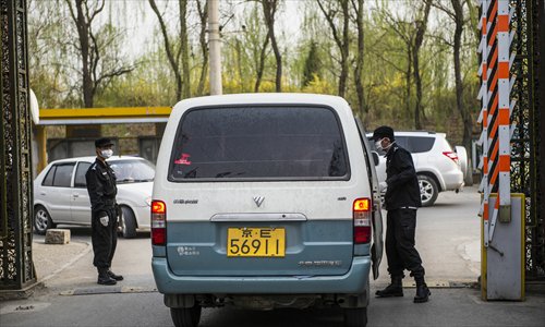 Security guards wearing masks check whether a van is carrying live poultry at the entrance to Naidong village, in Chaoyang district, Beijing, on Monday. The municipal health authorities announced on Monday a four-year-old boy surnamed Zhu from the village was an H7N9 flu virus carrier. Photo: Li Hao/GT