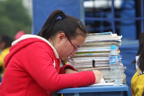 Gao Ying, a high school student, studies to prepare the college entrance exam this summer outside tents at a temporary settlement at the Tianquan Middle School in quake-hit Tianquan County, Ya'an City, southwest China's Sichuan Province, April 22, 2013. A 7.0-magnitude earthquake jolted Lushan County of Ya'an City in the morning on April 20. (Xinhua/Xing Guangli)