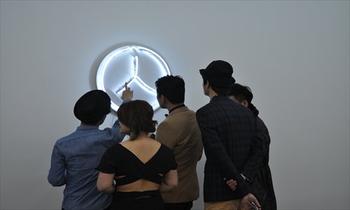 Visitors look at a neon wall artwork at the opening ceremony of the exhibition.