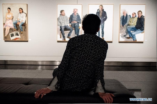 A visitor looks at paintings by Chen Danqing during the 